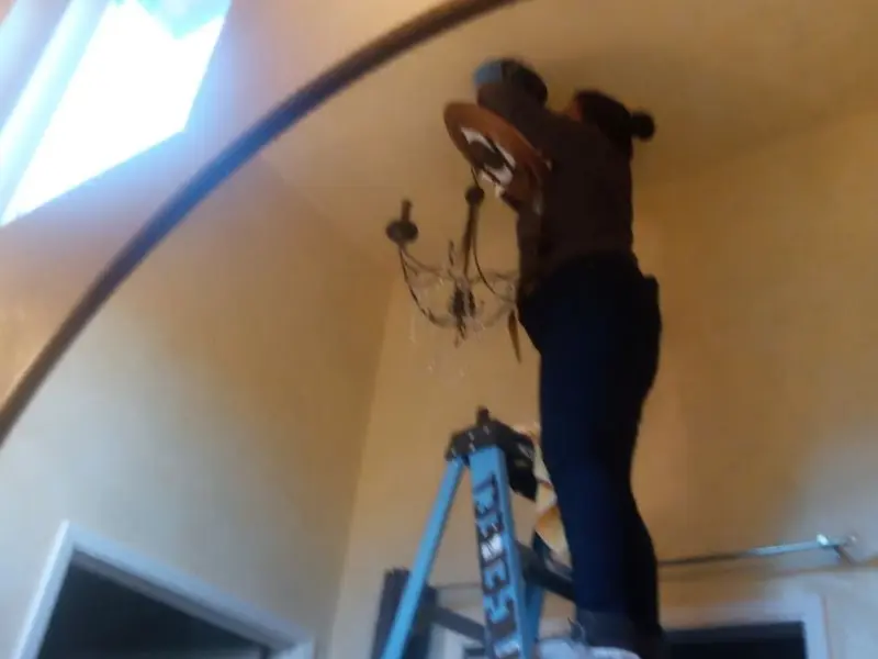 Electrician installing a chandelier in a Longbranch residence